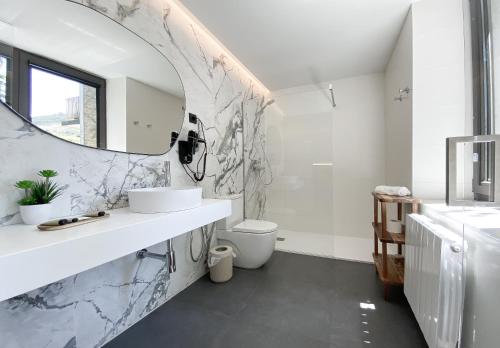 a bathroom with a sink and a toilet and a mirror at Hotel Arimune in Bakio