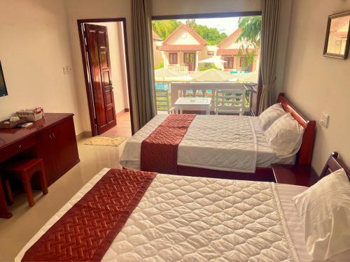 two beds in a bedroom with a view of a balcony at Hong Bin Bungalow in Phu Quoc
