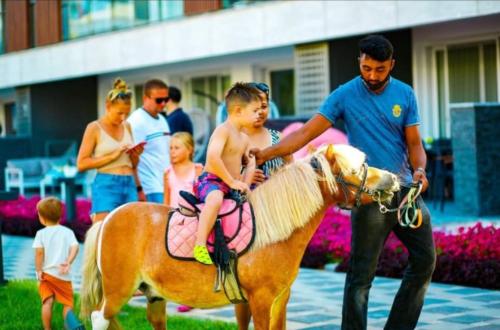 a man holding a little boy on a pony at Courtyard Long Beach Holiday Resort in Iskele