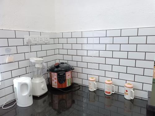 a kitchen with white tiled walls and a blender at Aila Homestay Pendang in Pendang