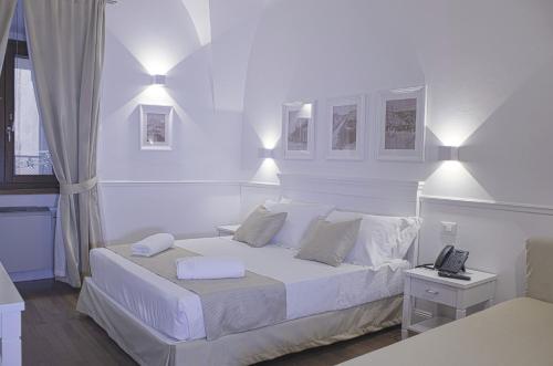 a white bedroom with a bed and a phone on it at Palazzo Sant'Elena in Foggia