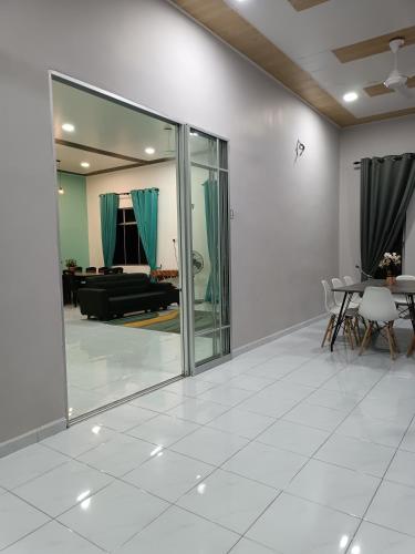 a living room with sliding glass doors and a table at Aila Homestay Pendang in Pendang