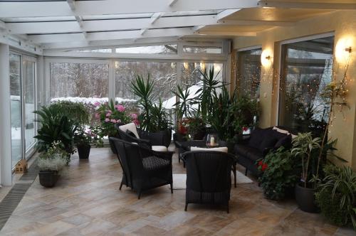 a conservatory with chairs and tables and plants at Jaunkrastmaļi in Kandava