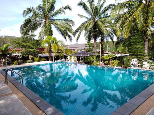une grande piscine avec des palmiers en arrière-plan dans l'établissement Palm Tian Home A7, à Ban Chong Phli