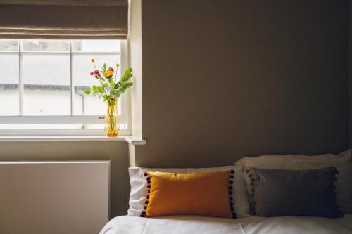 a vase of flowers sitting on a window sill next to a bed at Llety Arall in Caernarfon