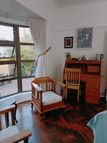 a living room with a desk and chairs and a window at John Bauer Pottery Studio in Cape Town