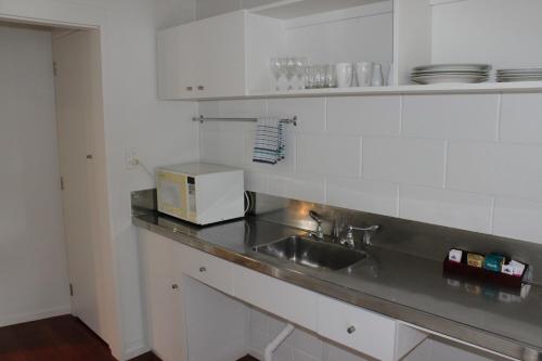 a kitchen with a sink and a microwave on a counter at Akaroa Village Inn in Akaroa