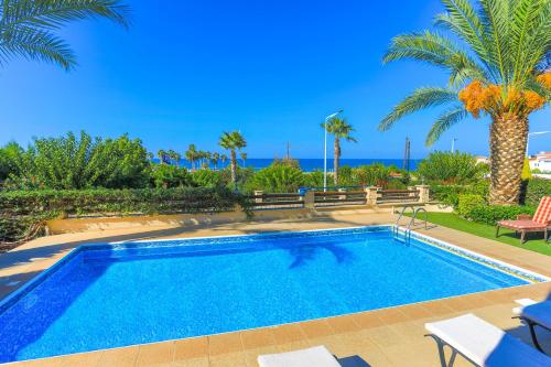 a swimming pool with palm trees and the ocean at Villa Arbanassi in Lachi