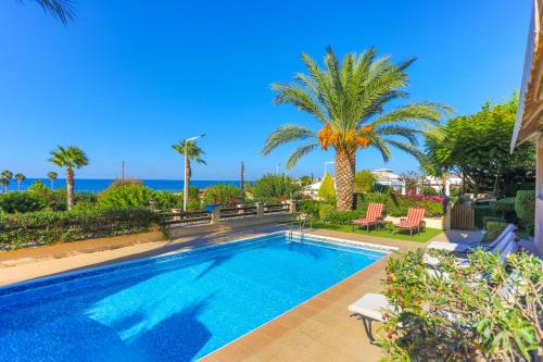 a swimming pool with palm trees and the ocean at Villa Arbanassi in Lachi