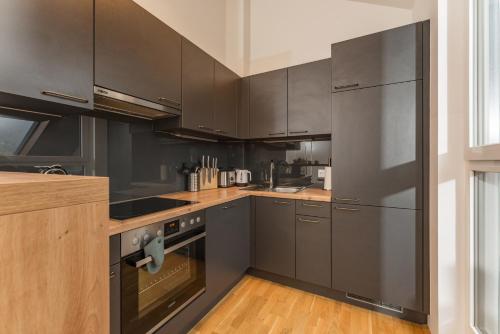 a kitchen with stainless steel appliances and wooden floors at APSTAY Eggenberg I Self Check-in I Parking option in Graz