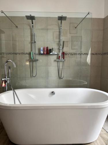 a white bath tub with a shower in a bathroom at Le Marronnier in Saint-Geniès-de-Fontedit
