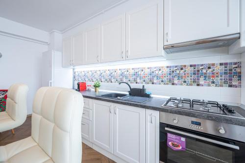 Una cocina blanca con fregadero y estufa. en Brick Flats, en Oradea