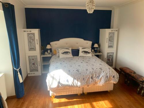 1 dormitorio con 1 cama con pared azul en La Douce France Trianon, en Chinon