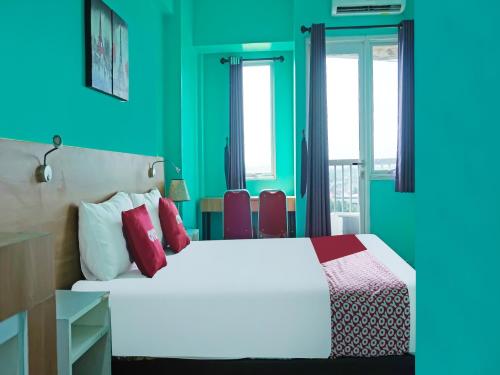 una camera con letto bianco e pareti verdi di OYO 90391 Gkitroom a Karawang