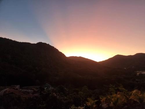 a sunset over a mountain range with the sun setting at Mirella Villa Ocean View Villa in Anse Possession