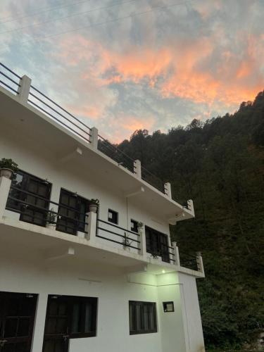 un edificio con un balcón con puesta de sol en el fondo en Chirag Homestay Kainchi, en Nainital