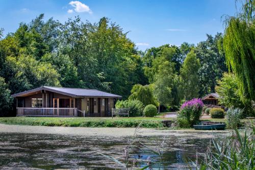 a cabin in a park next to a body of water at Willowbank Lodges in Oare