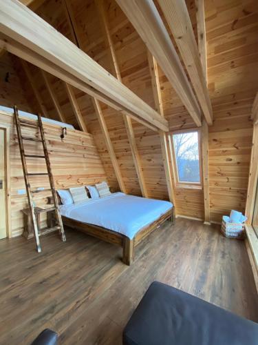 1 dormitorio en una cabaña de madera con cama y escalera en Cabana Masiv en Comăneşti
