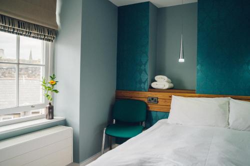 a bedroom with blue walls and a bed and a chair at Llety Arall in Caernarfon