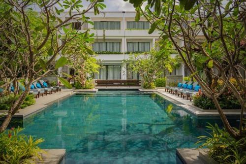 a swimming pool in front of a building with trees at Eightfold Urban Resort in Siem Reap