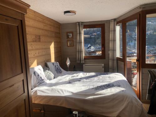 1 dormitorio con 1 cama grande con sábanas blancas en L'OURALOU - Vue panoramique en Les Gets