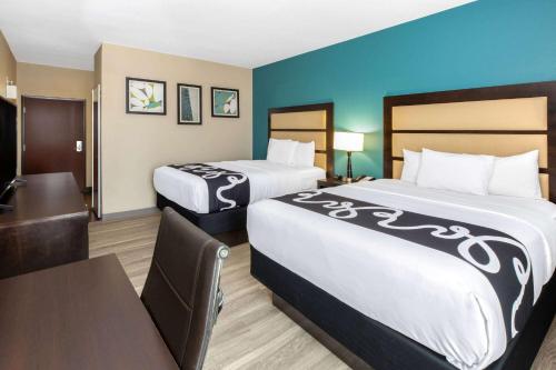 a hotel room with two beds and a table at La Quinta Inn & Suites by Wyndham Durant in Durant