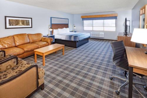 a hotel room with a couch and a bed at AmericInn by Wyndham Sayre in Sayre