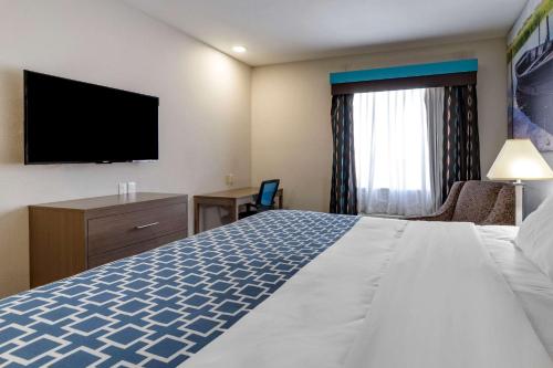 a hotel room with a bed and a flat screen tv at Clarion Pointe Sulphur - Lake Charles in Sulphur