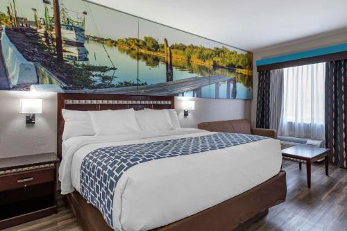 une chambre d'hôtel avec un lit et un tableau sur le mur dans l'établissement Clarion Pointe Sulphur - Lake Charles, à Sulphur