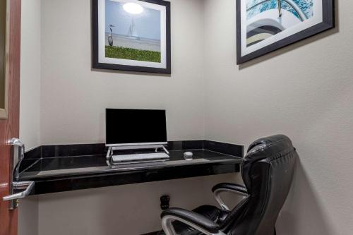 a desk with a computer on a wall with a chair at Clarion Pointe Sulphur - Lake Charles in Sulphur