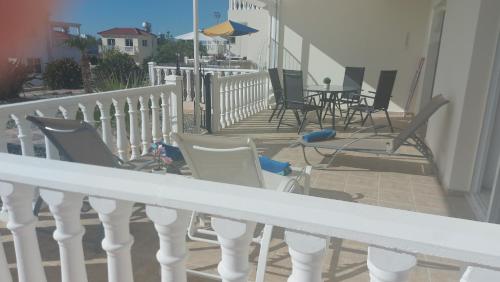 Un balcón con sillas y mesas en una casa en Nissi Golden Sands Sunny Apartment A1D4, en Ayia Napa