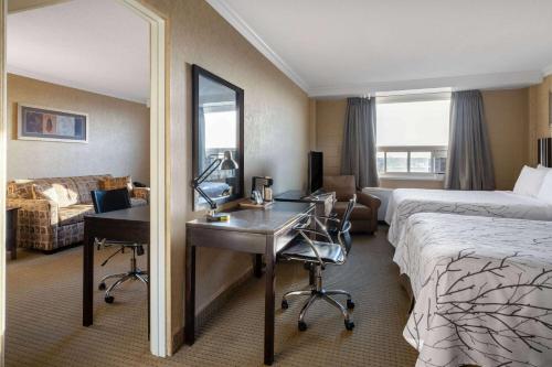 a hotel room with a desk and a bed and a mirror at Travelodge by Wyndham Prince Albert in Prince Albert