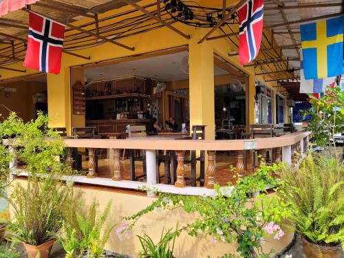 a restaurant with flags and plants in front of it at 2 Vikings Guesthouse in Karon Beach