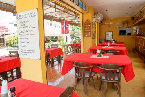 a restaurant with red tables and chairs and a sign at 2 Vikings Guesthouse in Karon Beach