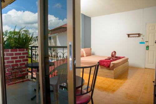 a room with a balcony with a table and a couch at 2 Vikings Guesthouse in Karon Beach