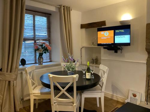 a dining room with a table and a tv on the wall at Carr’s cottage Eyam Peak District, in Eyam
