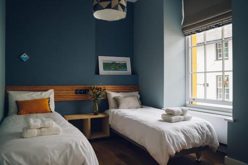 2 Betten in einem Zimmer mit blauen Wänden in der Unterkunft Llety Arall in Caernarfon