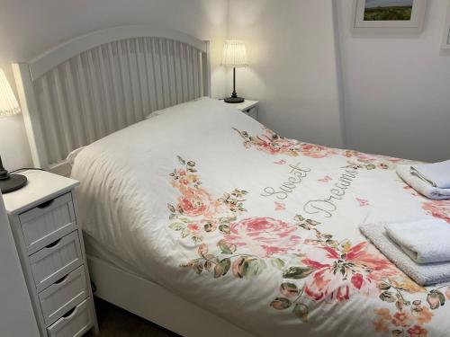 uma cama branca com um cobertor de flores em Carr’s cottage Eyam Peak District, em Eyam