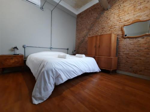 1 dormitorio con cama blanca y pared de ladrillo en Mendoza in en Mendoza