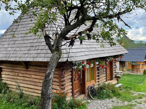 una cabaña de madera con un árbol delante en Complex Traditional Căsuța Bunicilor-Breb en Breb