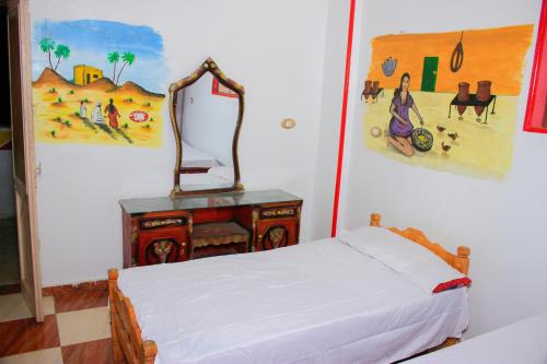 a bedroom with a bed and a mirror on a table at Hamo Guest House in Aswan