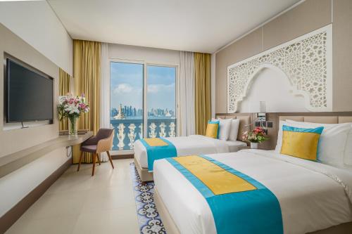 a hotel room with two beds and a television at Central Inn Souq Waqif in Doha