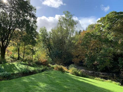 a lush green yard with trees and a river at River Cottage, a luxurious and cosy riverside cottage for two in Welshpool