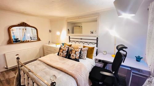 a bedroom with a bed and a desk and a mirror at Gold Room in Basildon