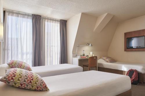Cette chambre comprend deux lits et une télévision. dans l'établissement Campanile Lyon Centre - Berges du Rhône, à Lyon
