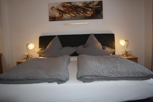 a bedroom with a bed with pillows and two lamps at Pension / Ferienwohnung Allebrodt in Lennestadt