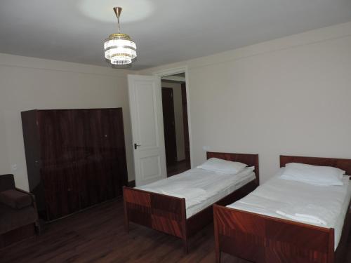 a bedroom with two beds and a chandelier at Guest House "Old House" in Tʼelavi
