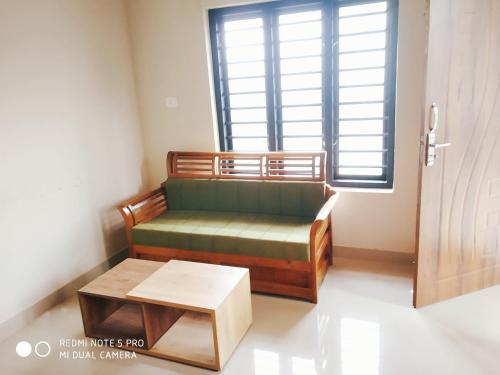 a living room with a green couch and a table at Eve's Residency home in Meppādi
