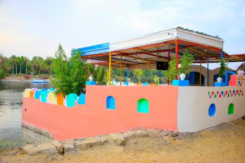ein farbenfrohes Haus an der Seite eines Wasserkörpers in der Unterkunft Hamo Guest House in Assuan