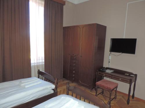 a bedroom with two beds and a desk and a television at Guest House "Old House" in Tʼelavi